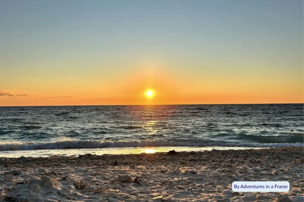 Golden sunrise over the ocean at Lady Elliot Island, Queensland, with gentle waves lapping the sandy shore.