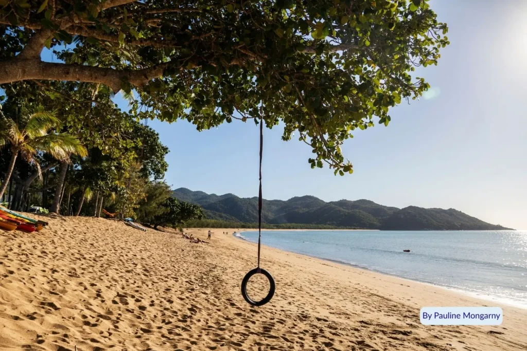 Tropical beach with tree swing overlooking calm turquoise water and forested hills on Magnetic Island, Queensland, Australia.
