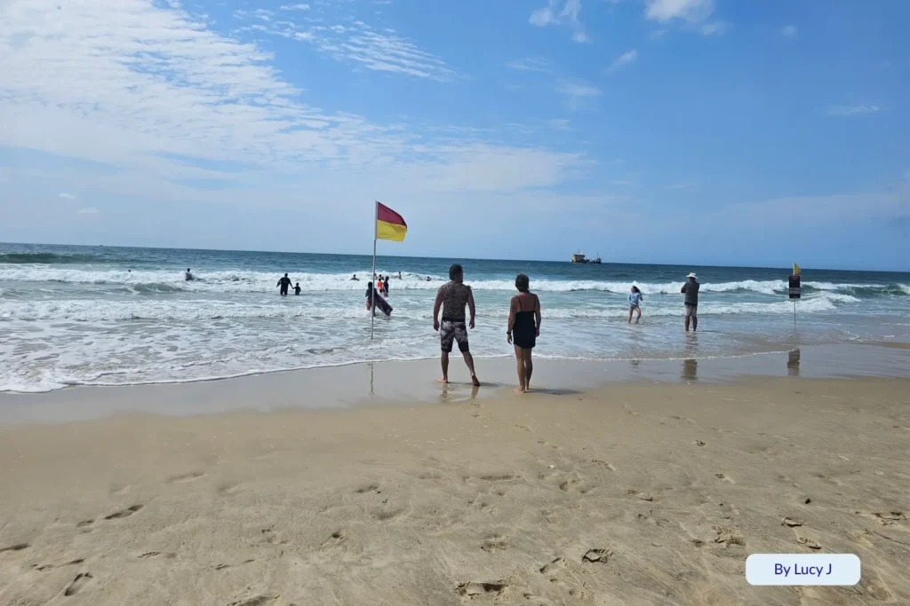Swimmers enjoying gentle surf between lifeguard flags at Main Beach, Southport, Gold Coast, Queensland, Australia, under blue summer skies
