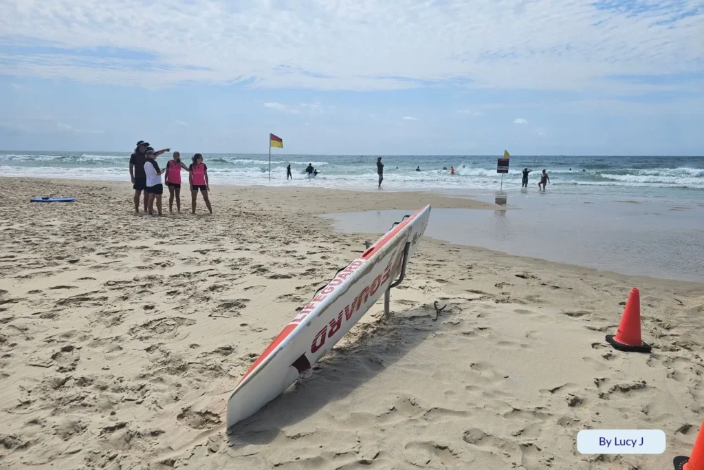 Lifeguard board and patrol cones on the sand as surf lifesavers watch swimmers at Main Beach, Southport, Gold Coast, Queensland