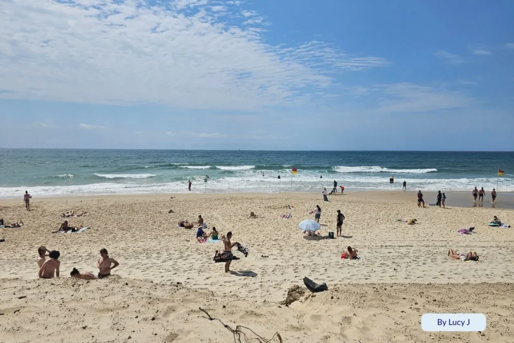 Beachgoers relaxing on the golden sand at Main Beach, Southport, with rolling waves and clear ocean views, Gold Coast, Queensland