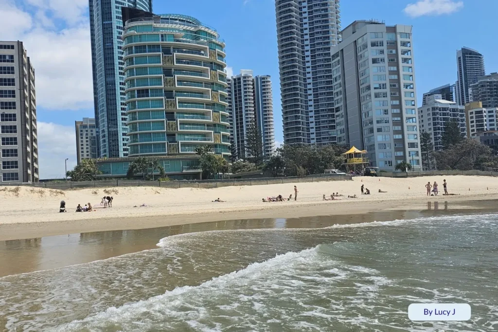 Waves rolling onto the golden sand at Northcliffe Beach with Surfers Paradise high-rises in the background, Gold Coast, Queensland, Australia.