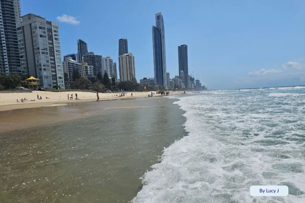 Foamy ocean waves at Northcliffe Beach stretching toward the Surfers Paradise skyline under clear blue skies, Gold Coast, Queensland