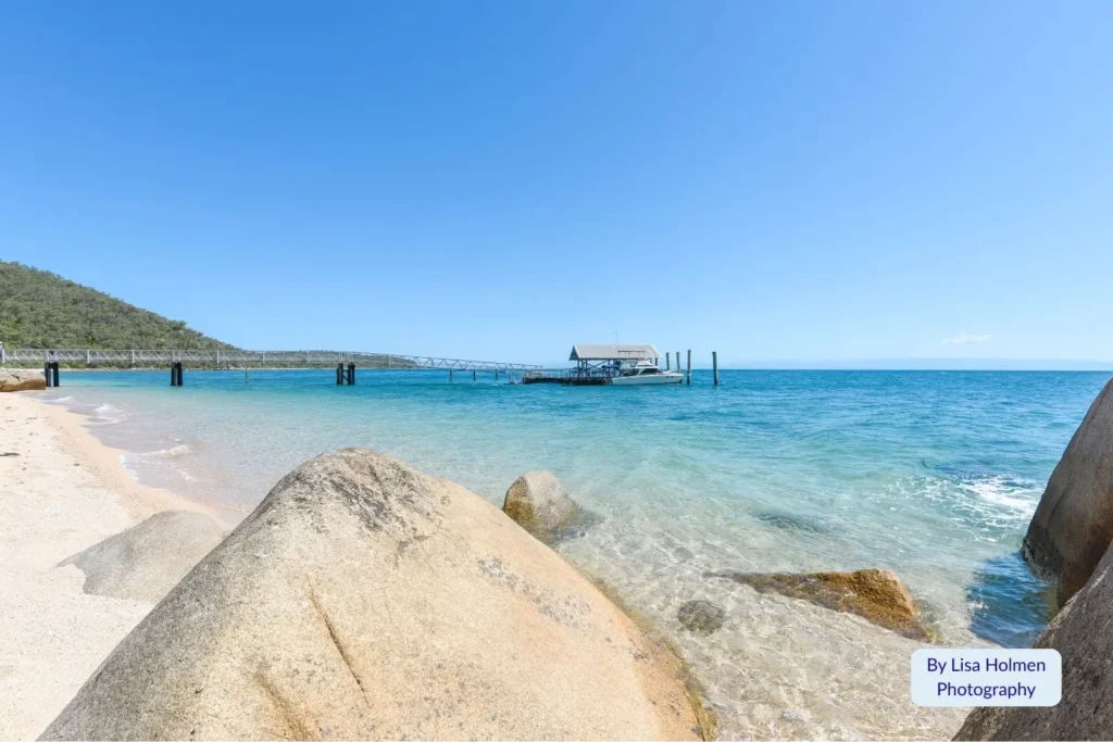 Crystal-clear ocean and wooden jetty beside granite boulders on Orpheus Island, Great Barrier Reef, North Queensland, Australia.