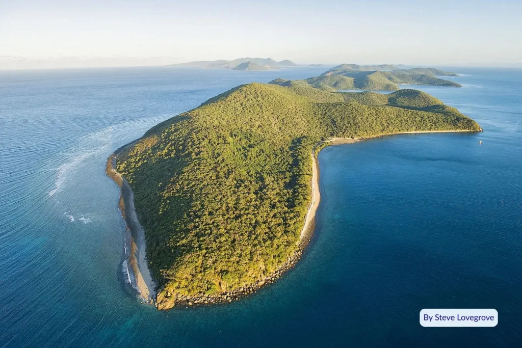 Aerial view of Orpheus Island surrounded by clear blue Coral Sea waters and lush green headlands, Great Barrier Reef, Queensland.