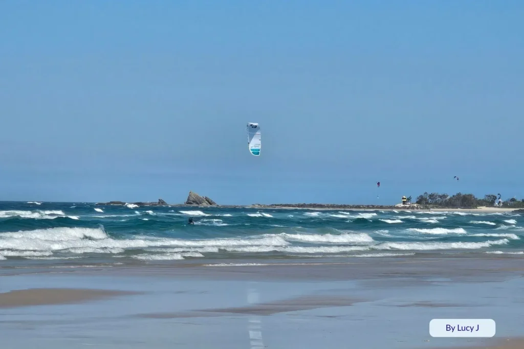 Kitesurfers gliding over turquoise waves at Palm Beach with Currumbin Rock in the distance, Gold Coast, Queensland, Australia