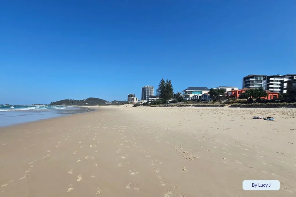Wide sandy stretch of Palm Beach with beachfront apartments and Burleigh Headland visible in the distance, Gold Coast, Queensland, Australia