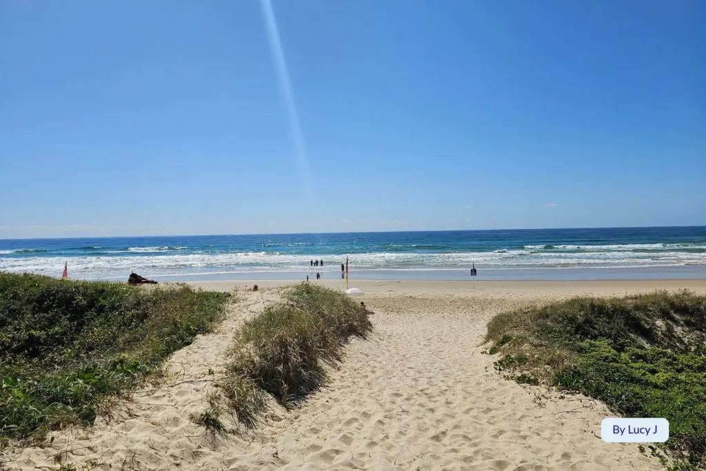 Sandy beach access track leading through coastal dunes to the blue waves of Peregian Beach, Sunshine Coast, Queensland, on a clear sunny day.