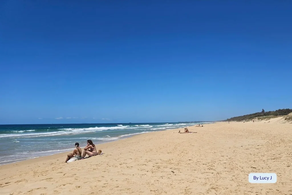 Peaceful morning at Point Cartwright Beach, Sunshine Coast, Queensland, with visitors relaxing on golden sand under a bright blue sky.