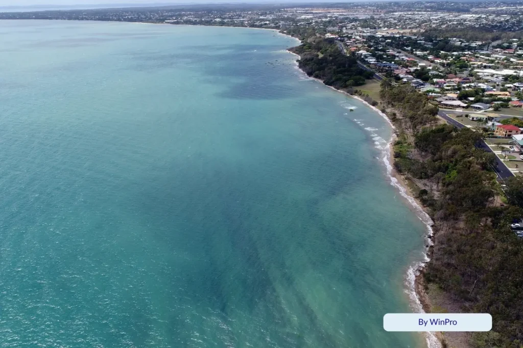Aerial view of Point Vernon, Hervey Bay, Queensland, showing turquoise coastal waters, rocky foreshore, and residential houses lining the scenic Fraser Coast shoreline