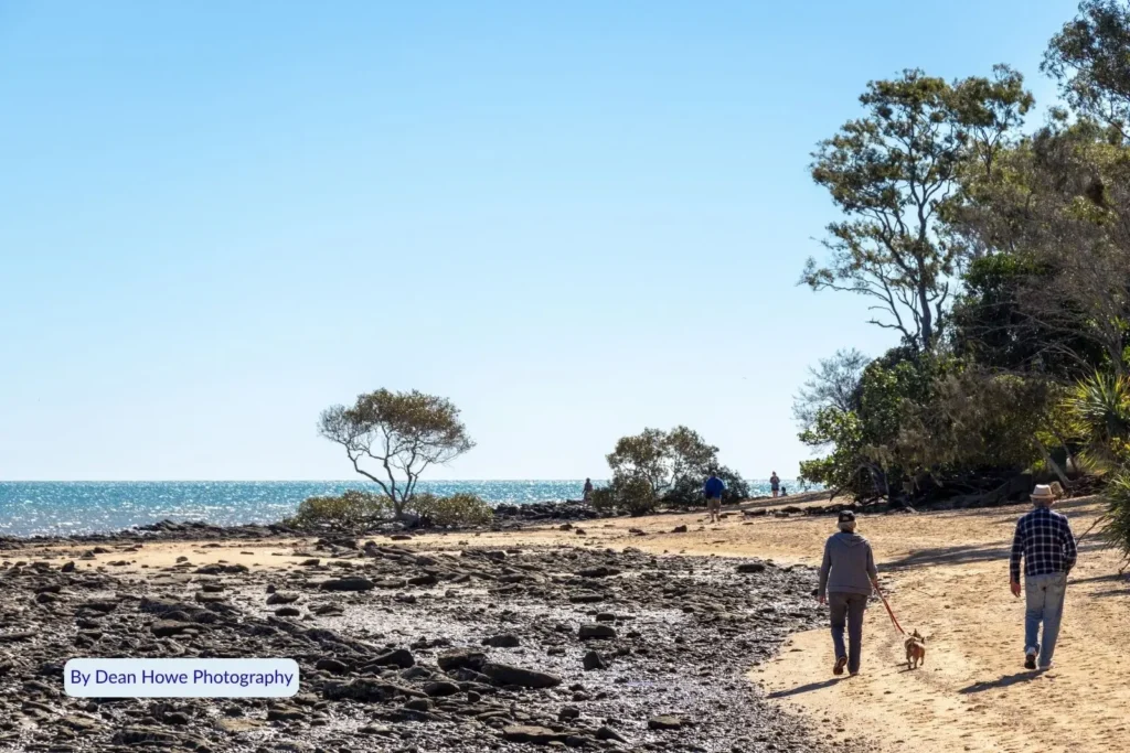 Visitors walking their dog along the rocky foreshore at Point Vernon, enjoying coastal views and natural scenery in Hervey Bay Queensland.