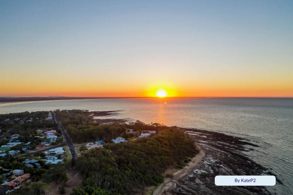 Golden sunset over Point Vernon and the Great Sandy Strait, with coastal homes and rocky foreshore glowing in evening light, Hervey Bay Queensland.