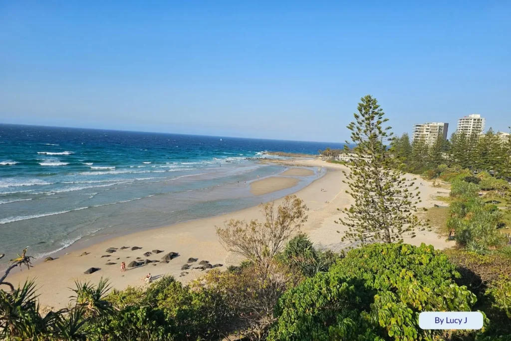 Scenic view over Rainbow Bay with turquoise waves, sandy shoreline, and lush coastal greenery near Snapper Rocks, Gold Coast, Queensland, Australia