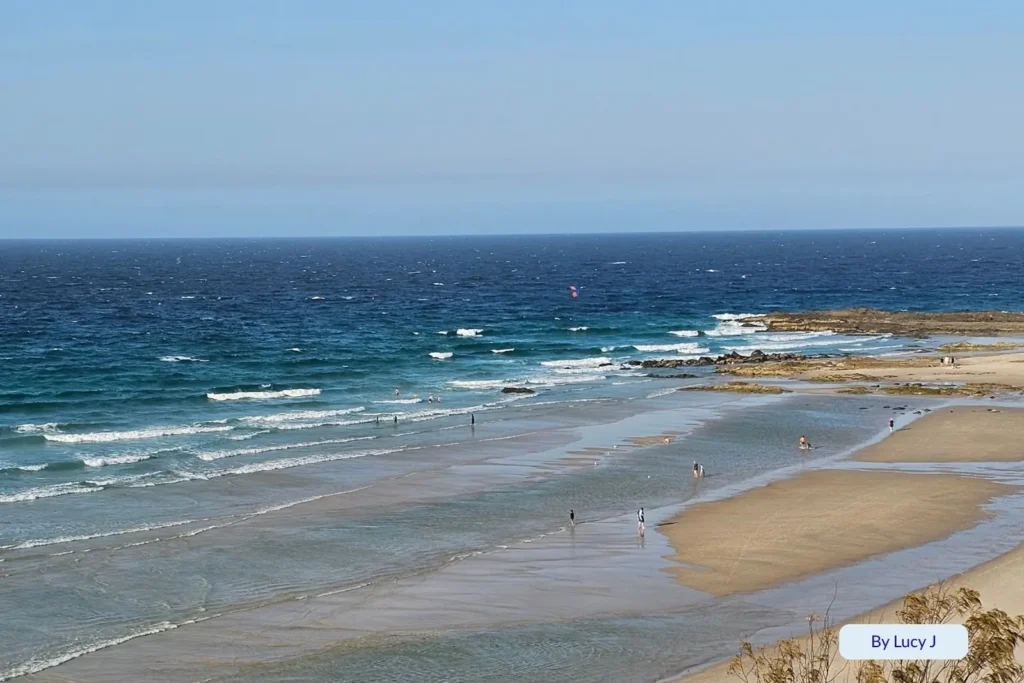 Crystal-clear shallows and gentle surf at Rainbow Bay with swimmers and surfers enjoying calm ocean conditions near Snapper Rocks, Gold Coast, Queensland.