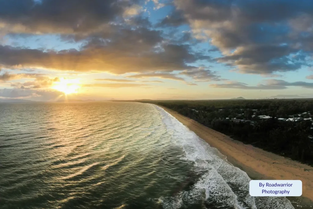 Sunset over Saunders Beach with golden light reflecting on waves and long sandy shoreline near Townsville, Queensland, Australia.