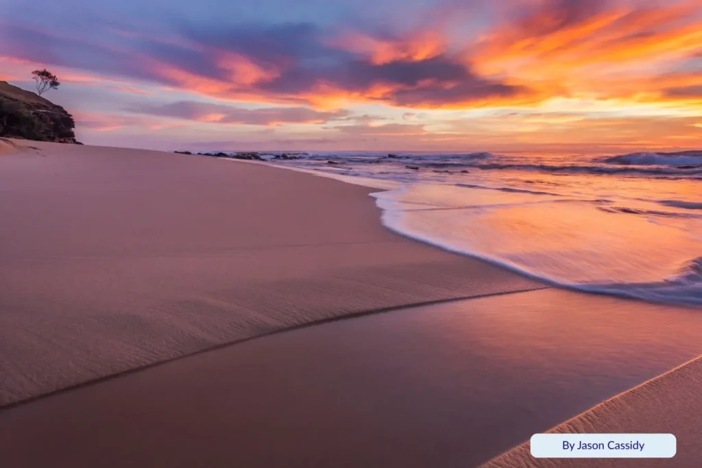 Sunrise over Shelly Beach, Sunshine Coast, Queensland — pink and orange sky reflecting on wet sand and gentle waves rolling across the shoreline.