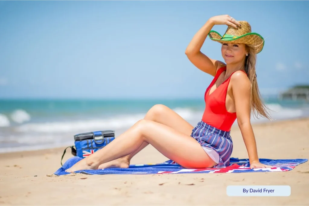 Woman relaxing on the golden sand at Shelley Beach, Torquay, Hervey Bay, Queensland, on a sunny day with calm blue water and clear skies in the background.