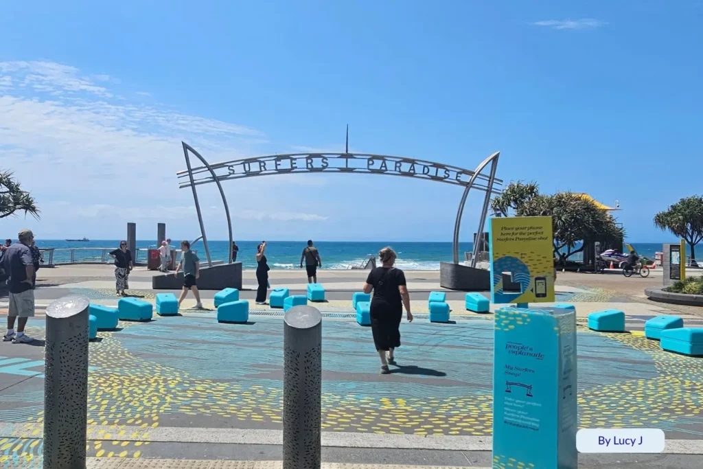Tourists walking near the iconic Surfers Paradise Beach archway on the Esplanade under bright sunshine, Gold Coast, Queensland, Australia
