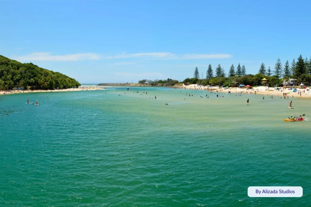 Families swimming, kayaking, and paddleboarding in the calm turquoise waters of Tallebudgera Creek, Gold Coast, Queensland, on a sunny summer day.