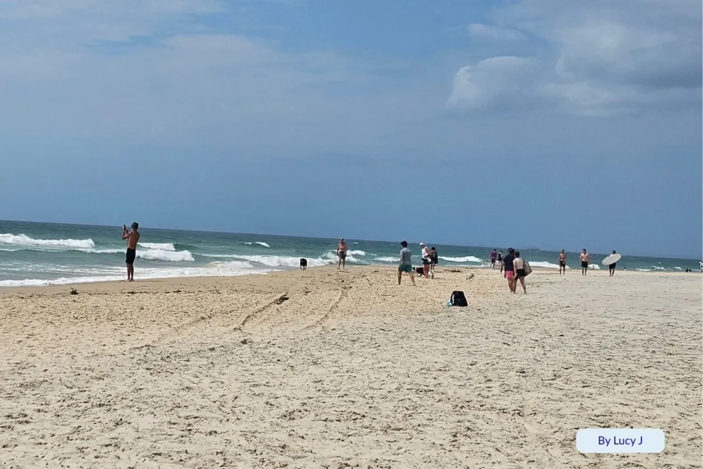 Beachgoers and surfers enjoying sunny conditions and ocean waves at The Spit, near Main Beach on the Gold Coast, Queensland