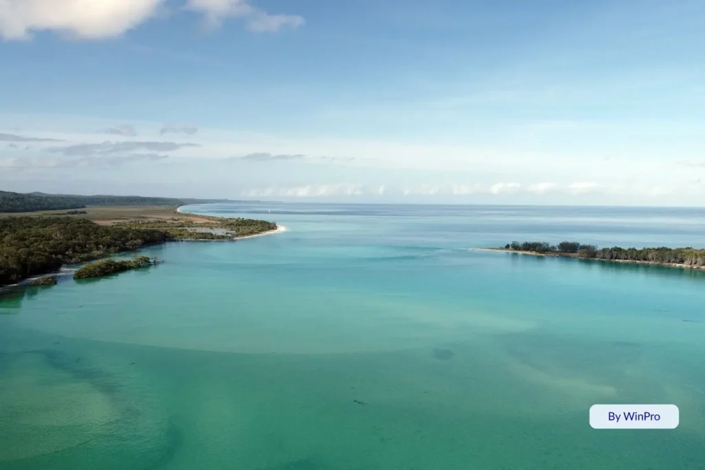 Aerial view of Wathumba Creek on Fraser Island (K’gari) showing turquoise tidal waters, white sandbanks, and lush coastal forest meeting Platypus Bay.