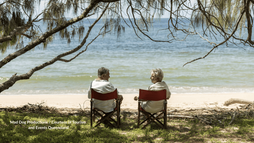 Couple sitting on Woodgate Beach Bundaberg under oak trees, Queensland