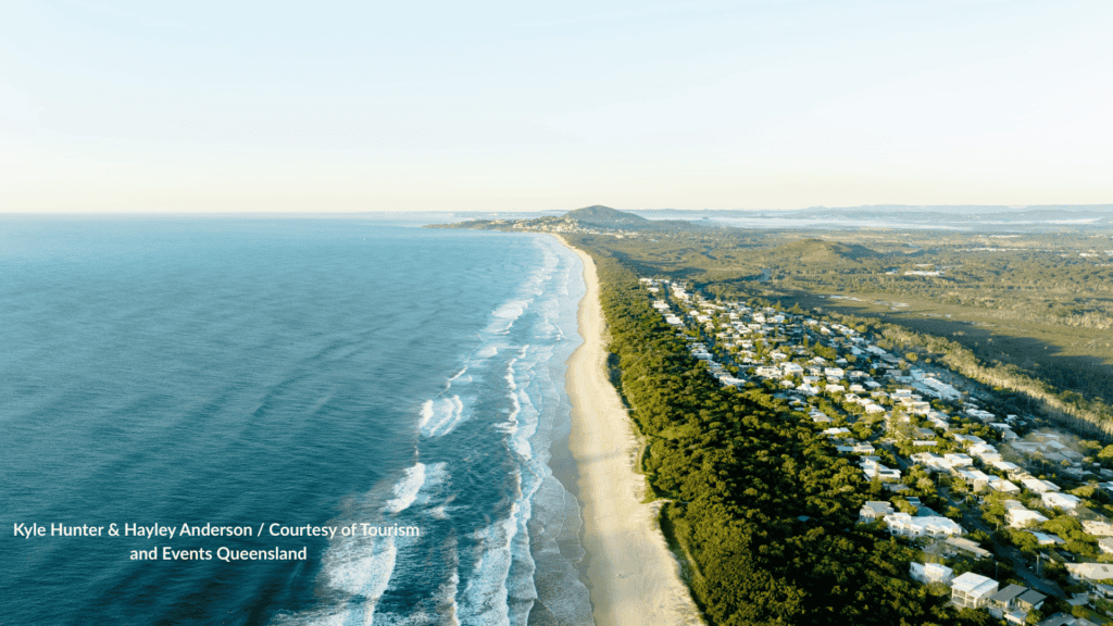 Aerial view of Peregian Beach Sunshine Coast Queensland looking along the long surf beach and tree lined hinterland houses toward the headland