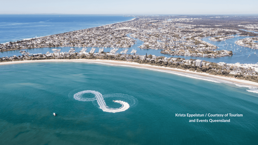 Aerial view of Mooloolaba Beach Sunshine Coast Queensland with a boat wake in front of the sand and Mooloolaba Harbour canals behind the esplanade