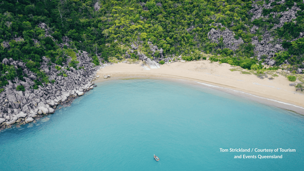 Aerial view of Shelving Beach on Great Keppel Island Queensland with the small sandy cove, granite rocks and a boat in the turquoise water