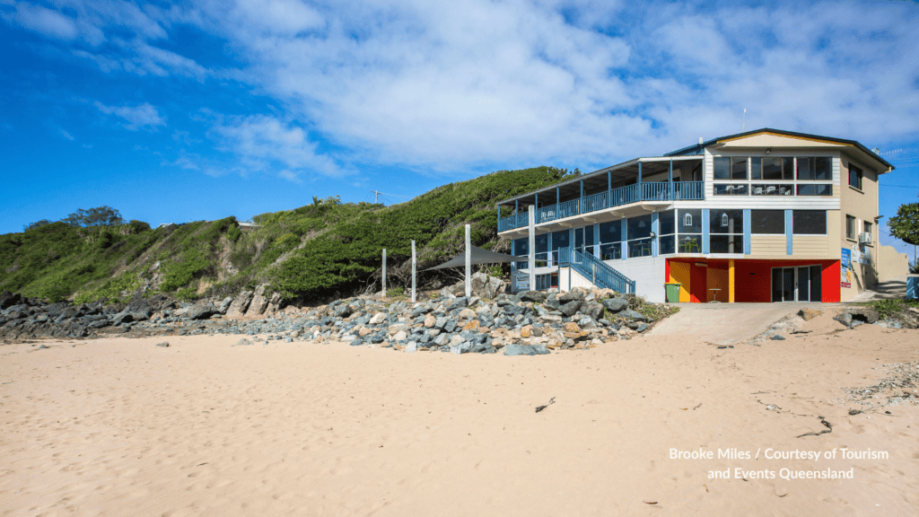 Sarina Beach Surf Life Saving Club sitting on the sand beside the rock wall and hillside at Sarina Beach Mackay Queensland