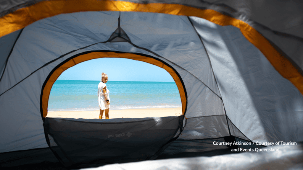 View from inside a beach tent at Ellis Beach Cairns Queensland with a woman standing on the sand facing the Coral Sea