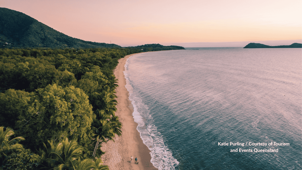 Aerial view of Clifton Beach Cairns Queensland at dusk with the long sandy shoreline, rainforest and palms, and an offshore island on the horizon