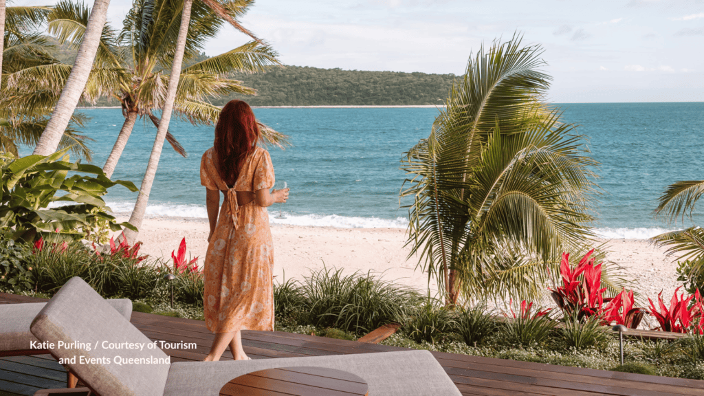 Woman standing on a villa deck looking out over the beach at Pelorus Island near Townsville Queensland