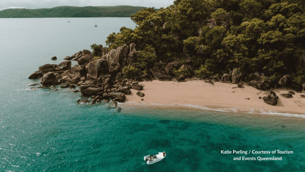 Aerial view of a small boat off a sandy granite cove at Orpheus Island near Townsville Queensland