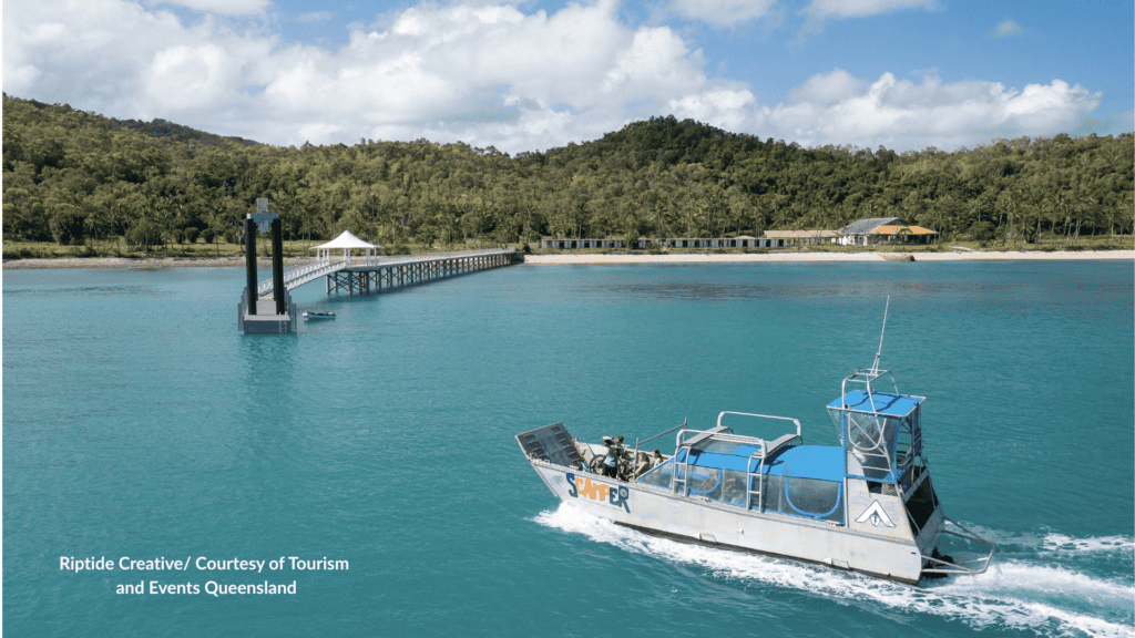 Transfer boat approaching the jetty at Bauer Bay South Molle Island Queensland with the old resort cabins along the beach
