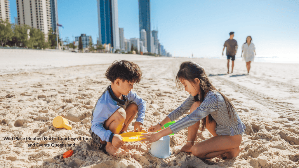 Queensland Kids building a sandcastle on Surfers Paradise Beach with the Gold Coast skyline behind