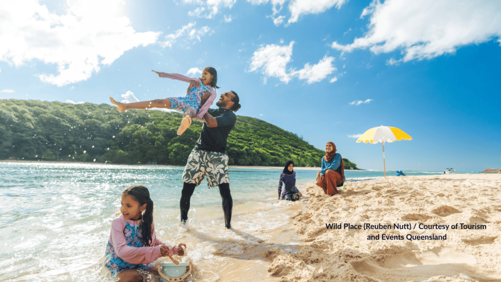 Family playing in the shallows at Tallebudgera Creek Beach under Burleigh Head National Park Queensland