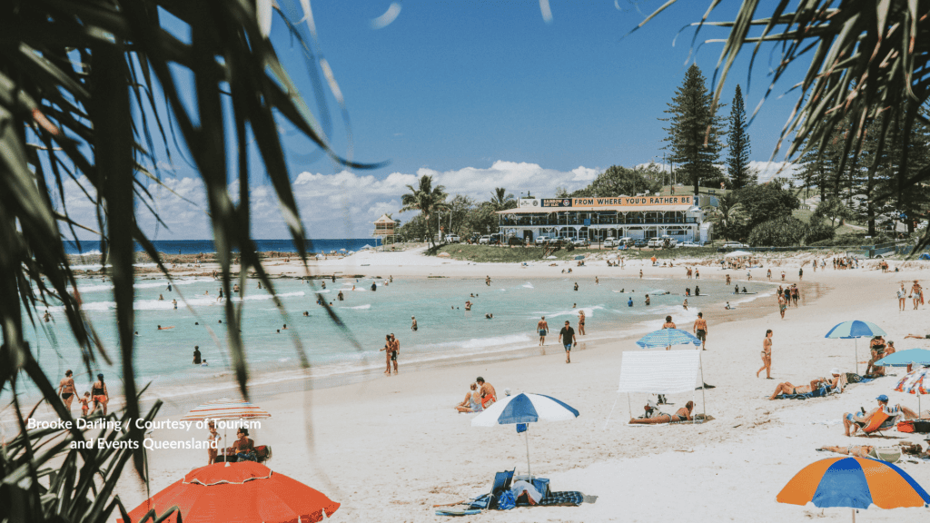 Crowds and umbrellas at Rainbow Bay Beach Gold Coast Queensland below the surf club