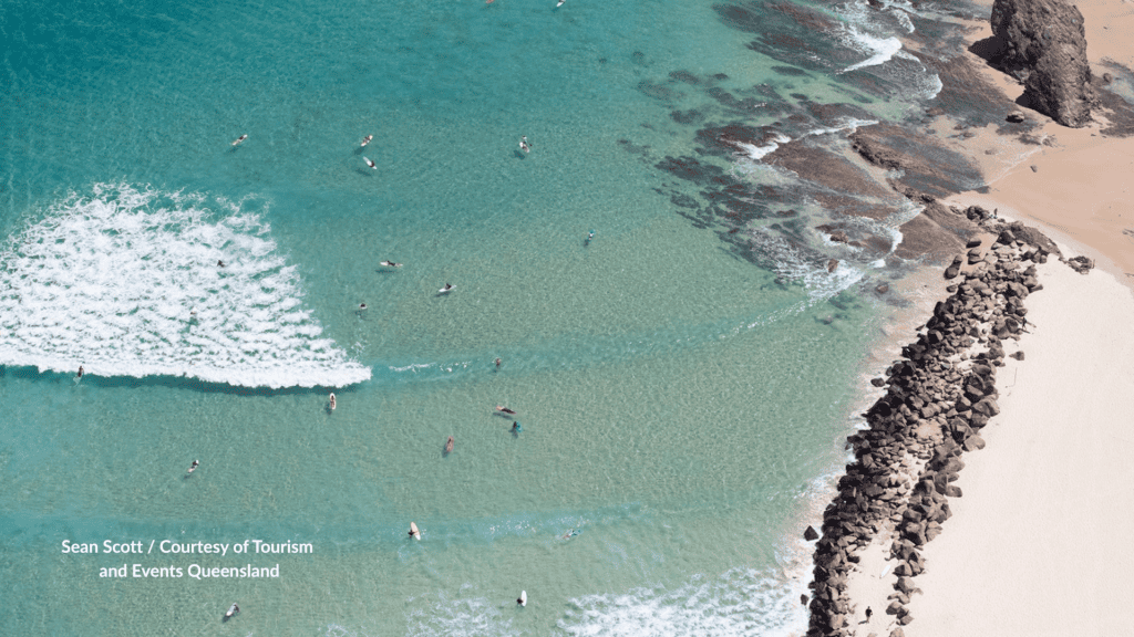 Aerial of surfers along the rock groyne at Duranbah Beach next to Snapper Rocks in Queensland