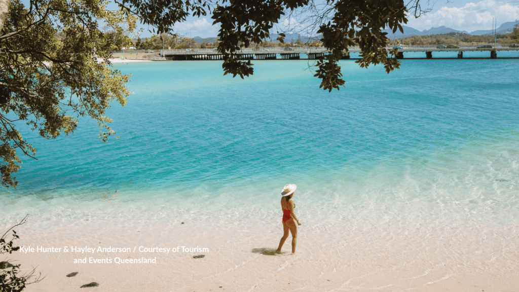 Woman walking into the shallows at Echo Beach Queensland toward the Gold Coast Highway bridge