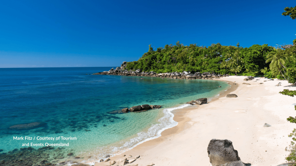 Stunning Bedarra Island in Queensland with white sand cove and granite rocks with clear water and a forested headland