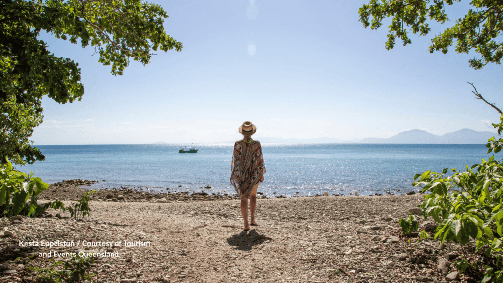 Pelorus Island Queensland rocky foreshore with a visitor facing the water a boat and distant hills