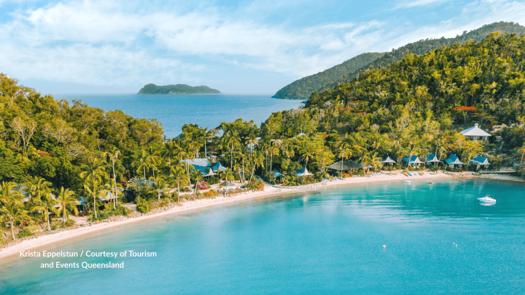 Queensland's Palm Bay Resort on Long Island Whitsundays palm-lined bay with beachfront huts and turquoise water under forested hills