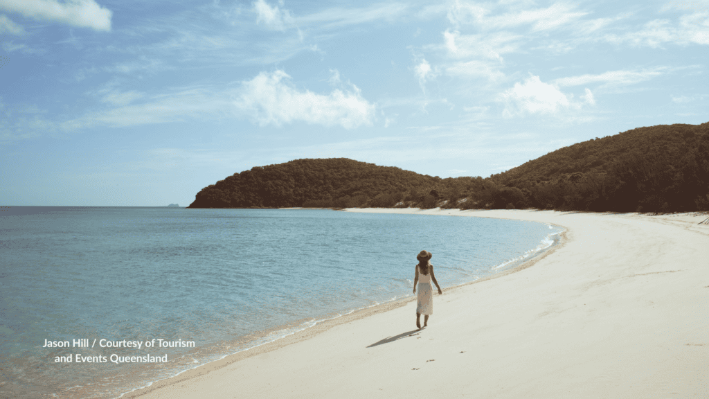 Chalkies Beach Haslewood Island Queensland white silica sand with a walker toward the forested headland