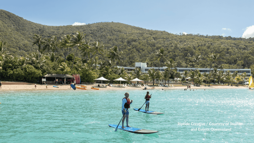 Stand up paddleboarding in front of Hayman Island Resort beach Whitsundays Queensland